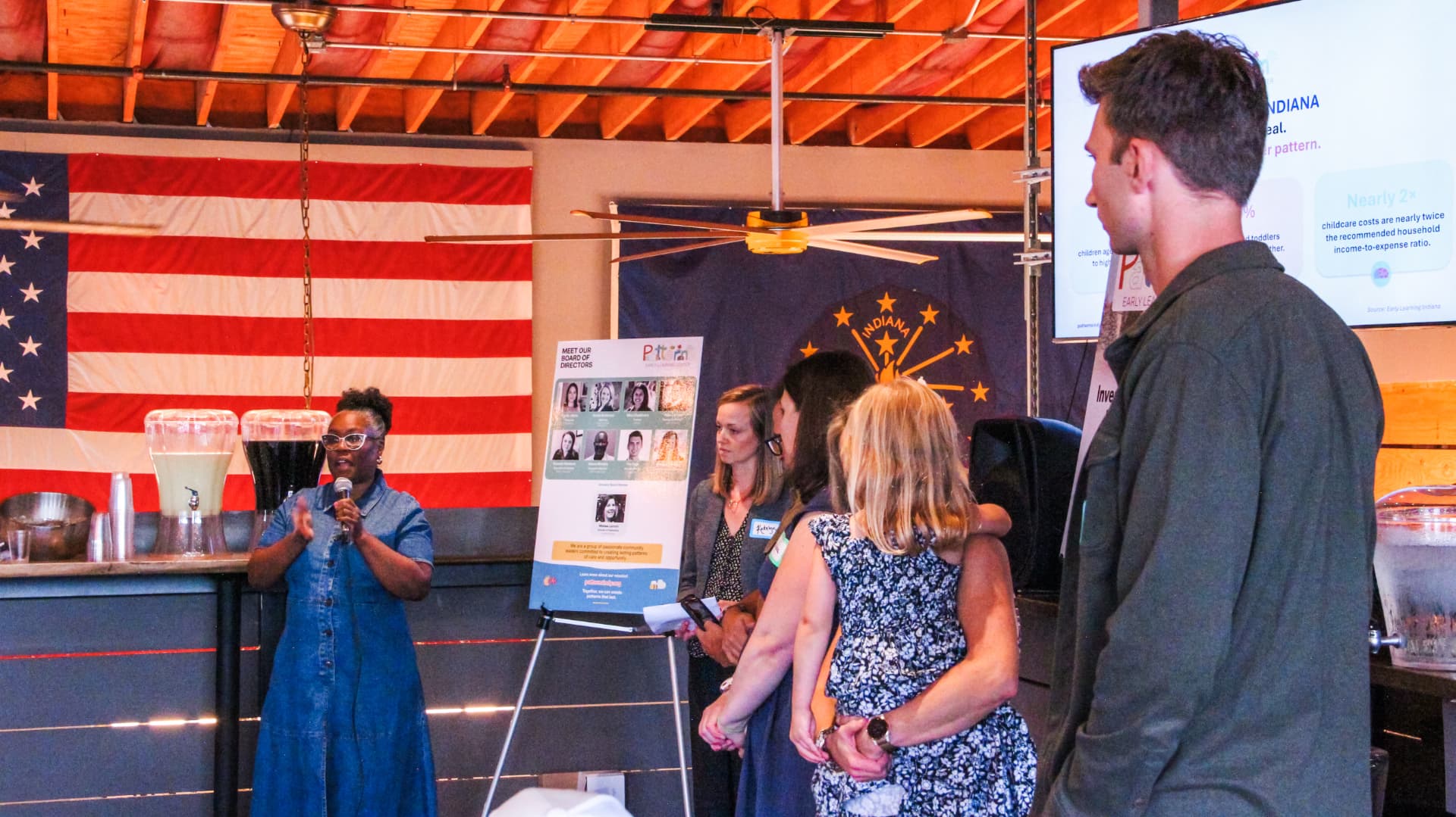 A board member speaking to guests in front of a slide about childcare costs in Indiana